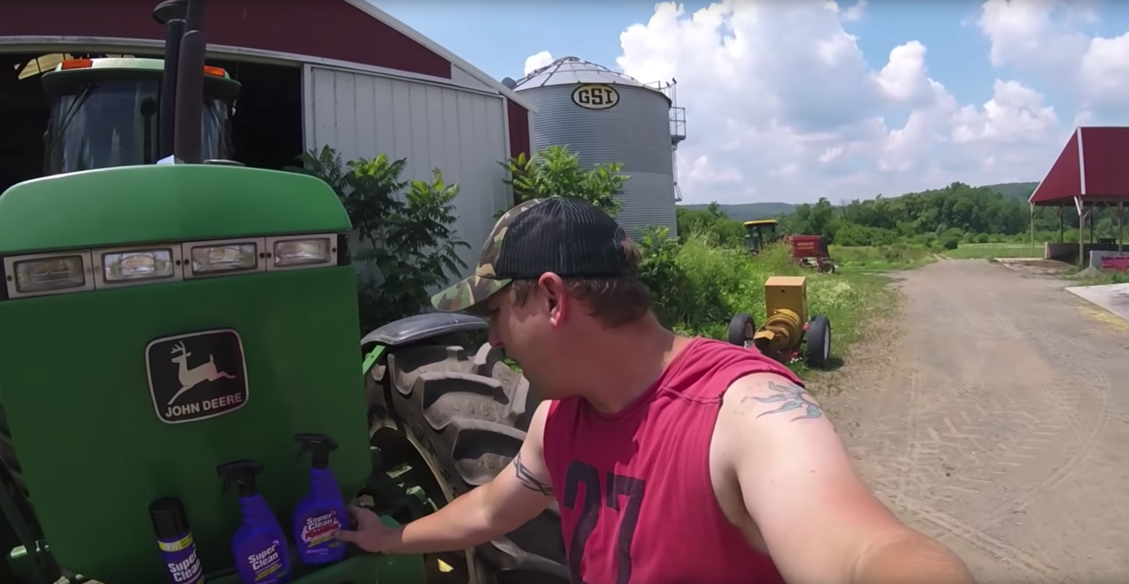 Farmer with hand on one of three bottles of Super Clean on tractor front
